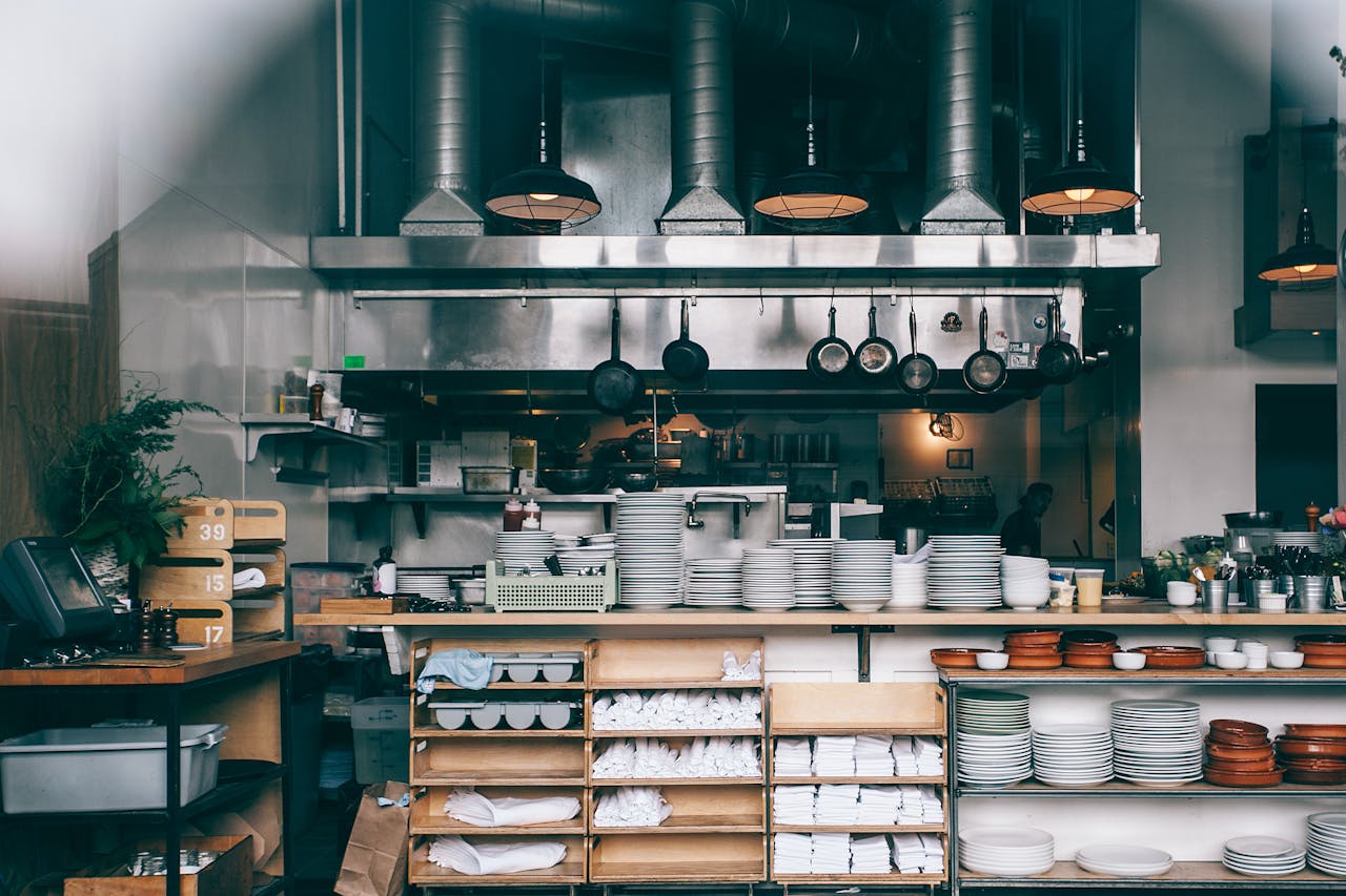 Interior of kitchen in modern restaurant with piles of plates and other different assorted utensils